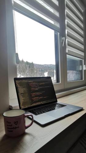 a laptop computer sitting on a table next to a window at Bjelašnica Vukov Vis 09 - apartment with a bedroom in Bjelašnica