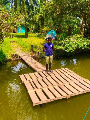 a man standing on a wooden bridge in the water at Wilpattu Green Cabin in Achchamulai