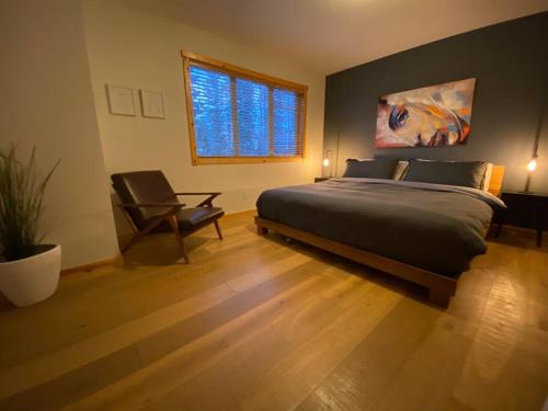 a bedroom with a bed and a chair and a window at Cozy Mountain Retreat w/ Private Hot Tub in Fernie