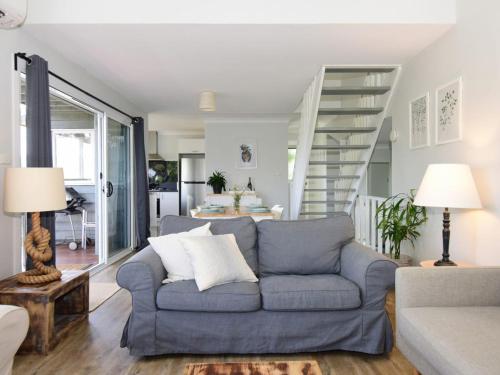 a living room with a blue couch and a staircase at Treetops - Three bedroom home with great views, in the village! in Kangaroo Valley