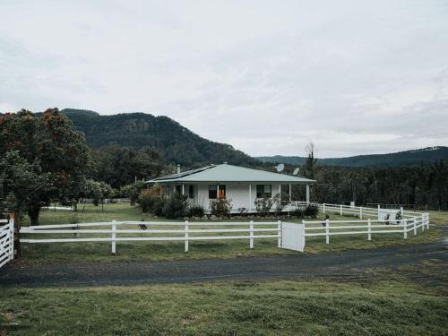 a white farm house with a white fence at The Hamilton Kangaroo Valley in Kangaroo Valley