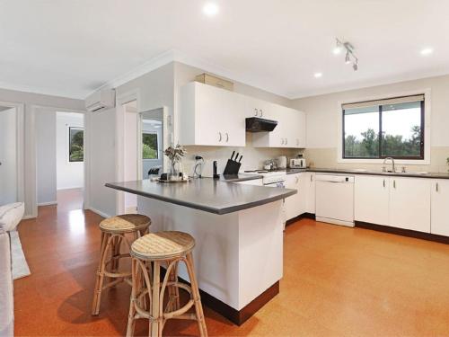 a kitchen with white cabinets and a large island with stools at The Hamilton Kangaroo Valley in Kangaroo Valley