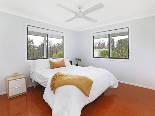 a white bedroom with two beds and two windows at The Hamilton Kangaroo Valley in Kangaroo Valley