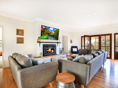 a living room with two couches and a fireplace at Wild Peace Mountain Lodge Kangaroo Valley in Bellawongarah
