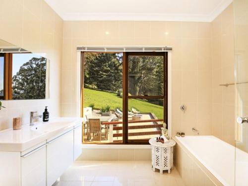 a bathroom with a tub and a sink and a window at Wild Peace Mountain Lodge Kangaroo Valley in Bellawongarah
