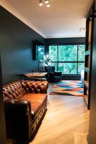 a living room with a leather couch and a table at The Blue Hotel Bondi in Sydney