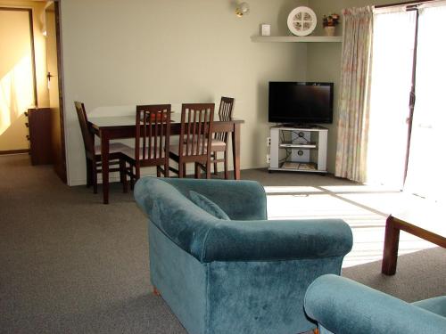 a living room with a couch and a table and chairs at 193 Aorangi Manor Motel in Blenheim