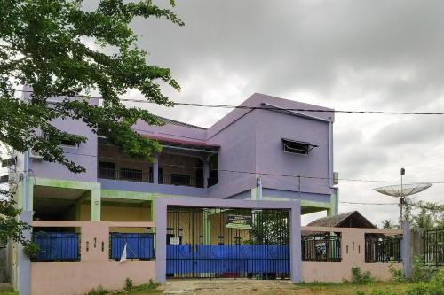 une maison violette avec une porte bleue devant elle dans l'établissement Habieb Homestay Syariah near Fakultas Kedokteran Universitas Malikussaleh Mitra RedDoorz, à Kadang