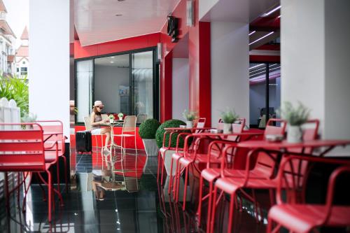 una mujer sentada en una mesa en un restaurante con sillas rojas en The Chilli Patong Beach Hotel - Near to the Beach -Completed Fully renovate 2023, en Patong Beach