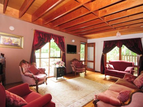 a living room with red chairs and a wooden ceiling at Orange Blossom Retreat in Kangaroo Valley