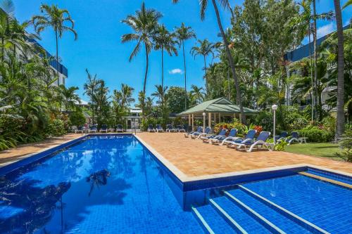 a pool at a resort with chairs and palm trees at Agincourt Beachfront Apartments in Clifton Beach