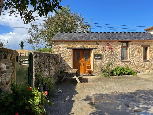 uma casa de pedra com uma porta de madeira e um banco em Estudio Pajar rural con bonito jardín - Los Gayoles Rural em Castropol