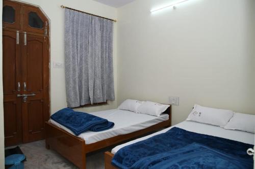 two beds in a small room with a window at Hotel Yash Paradise 6 Min Distance from Dargah in Ajmer
