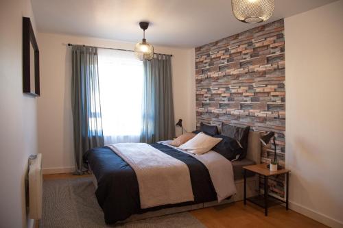 um quarto com uma cama e uma parede de tijolos em Modern 2 bed Apartment- Town Centre em Northampton