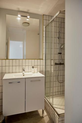 une salle de bain avec un lavabo blanc et une douche dans l'établissement Appartement front mer proche omaha & utah beach - 1, à Grandcamp-Maisy