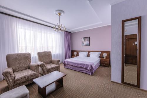 エッセントゥキにあるБизнес-отель "Эринии"のベッド、椅子、鏡が備わる客室です。