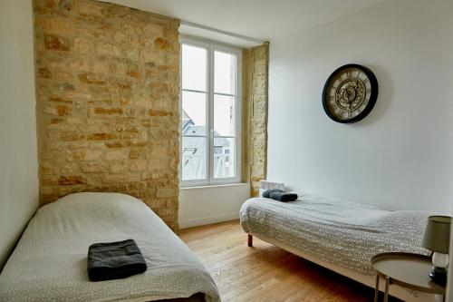 1 dormitorio con 2 camas y reloj en la pared en Appartement front mer proche omaha & utah beach - 2, en Grandcamp-Maisy