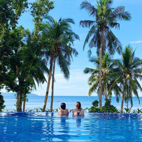 Dos mujeres en una piscina mirando al océano en Tuburan Cove Beach Resort, en Buruanga