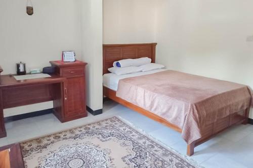 Schlafzimmer mit einem Bett, einem Schreibtisch und einem Waschbecken in der Unterkunft TRIYOGA Homestay Syariah RedPartner in Sangkanurip