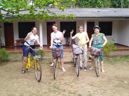 a group of women riding bikes in front of a house at Deer Garden Guest in Polonnaruwa