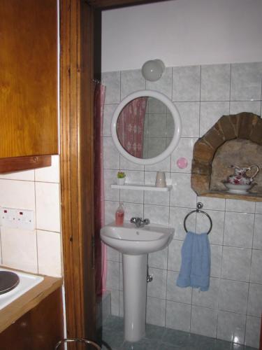 a small bathroom with a sink and a mirror at Vasilopoulos House in Tochni