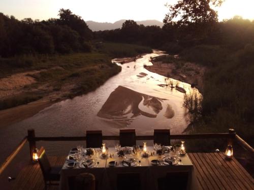 a table set up for a meal next to a river at Karongwe - Kuname Safari Lodge in Hoedspruit