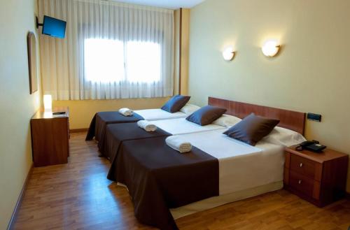 a hotel room with two beds and a window at Hotel Ciutat de Tarrega in Tárrega