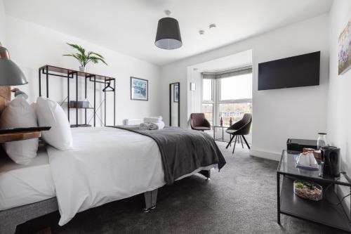 a white bedroom with a large bed and a tv at Seascape in Penzance