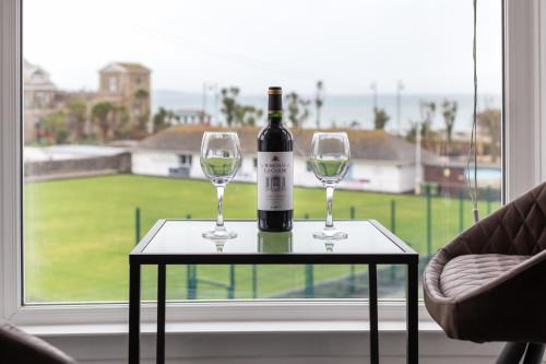 a bottle of wine sitting on a table with two glasses at Seascape in Penzance