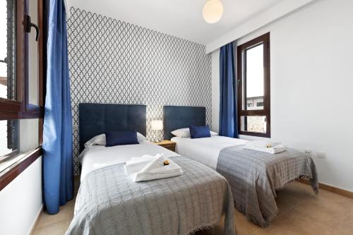 2 łóżka w pokoju z niebieskimi zasłonami w obiekcie Lanzarote Villa Arts w mieście Playa Blanca