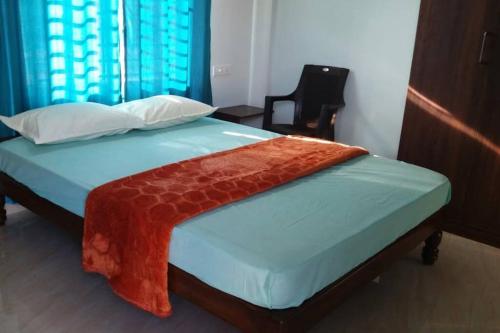 Una cama con una manta roja encima. en DWARAKA STAY INN-Rejoicing Family Home Coorg, en Kushālnagar