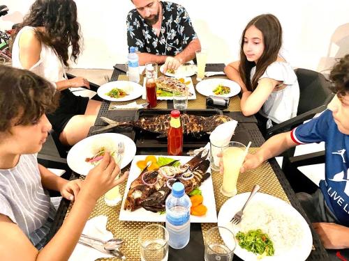 a group of people sitting around a table eating food at Thoddoo Island Life in Thoddoo