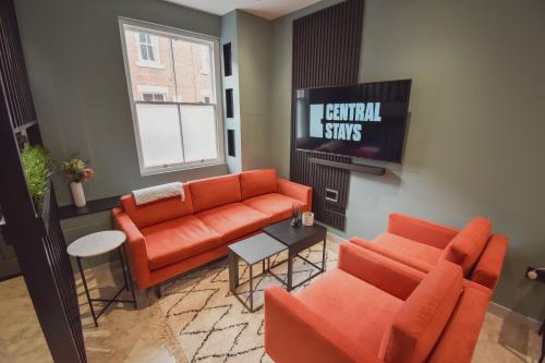 a living room with an orange couch and a tv at Central Stays - Luxury 3 Bedroom House in Central Chester SLEEPS 6 in Chester