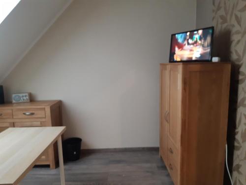 a room with a tv on top of a wooden cabinet at JaNettes Gästehaus in Bad Doberan