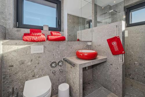 ein Badezimmer mit einem WC und einem roten Stuhl in der Unterkunft Lobster in Lubmin