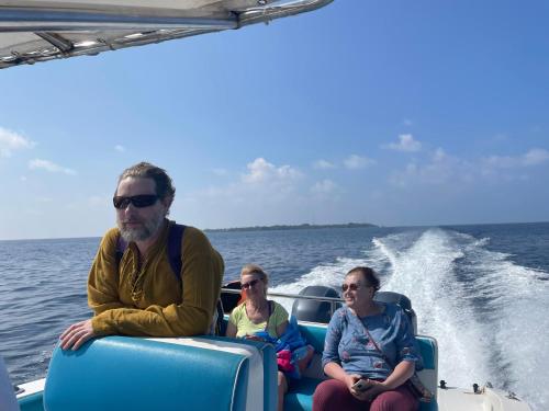 three people sitting on a boat in the water at Thoddoo Island Life in Thoddoo