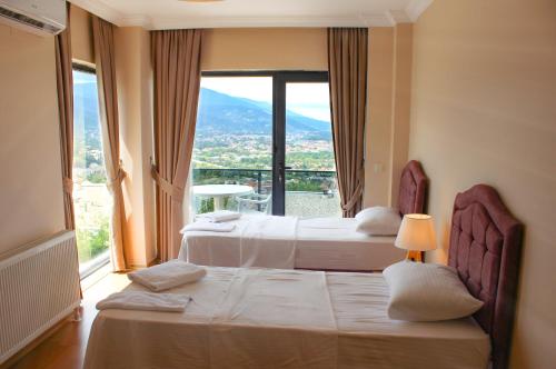 two beds in a room with a large window at Sawsana Villalari in Sapanca