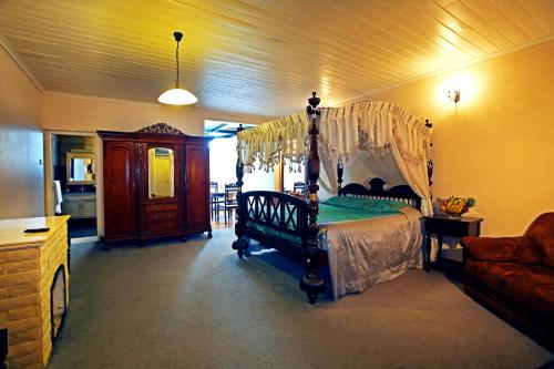 a bedroom with a canopy bed and a couch at The Firs in Nuwara Eliya