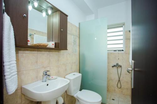 a bathroom with a white toilet and a sink at Tsampika's Sea View Home in Archangelos