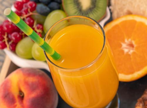 a glass of orange juice next to a bowl of fruit at Le President-Gare Nimes Pont Du Gard in Bellegarde