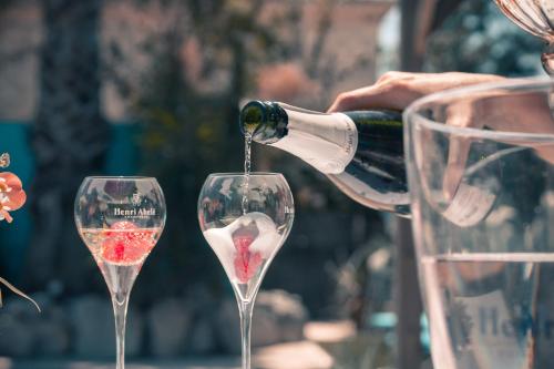 a person pouring a bottle of wine into two wine glasses at Le President-Gare Nimes Pont Du Gard in Bellegarde