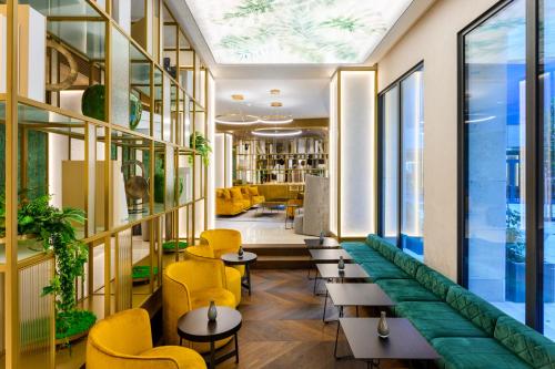 a lobby of a hotel with yellow chairs and tables at Emerald Downtown Luxury Suites with Hotel services in Budapest