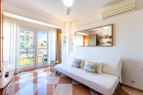 a living room with a couch and a large window at Sunny Seaside Apartment in Arroyo de la Miel