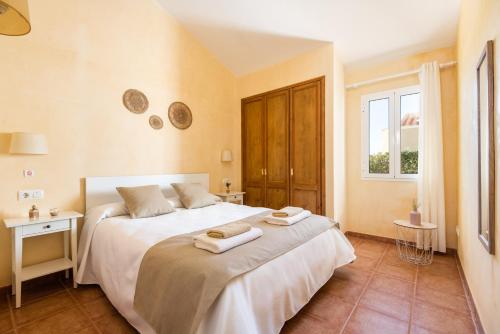 una camera da letto con un grande letto bianco con asciugamani di Villa Androna a Cala'n Bosch