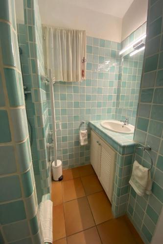 une salle de bain carrelée bleue avec un lavabo et une douche dans l'établissement Palombaggia, à Porto-Vecchio