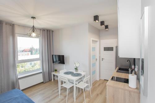 una pequeña cocina blanca con mesa y ventana en Urban Jungle - Grey Apartment, en Białystok