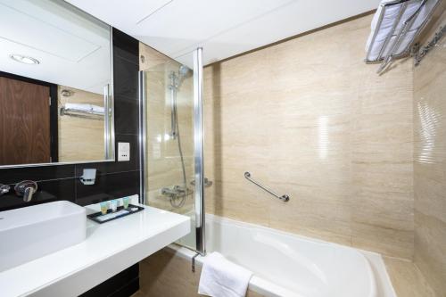 a bathroom with a tub and a sink and a shower at Pearl Swiss Hotel in Dubai