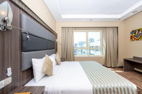 a hotel room with a bed and a window at Pearl Swiss Hotel in Dubai