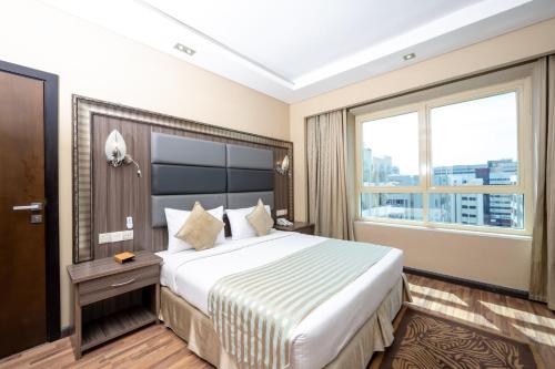 a hotel room with a large bed with a large window at Pearl Swiss Hotel in Dubai