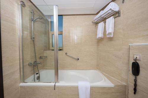 a bathroom with a bath tub and a shower at Pearl Swiss Hotel in Dubai